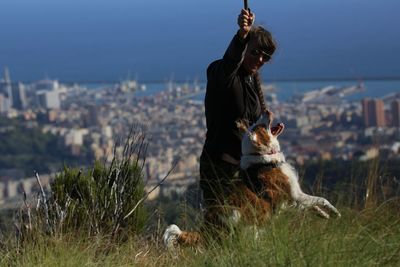 Woman with dog on field against sky