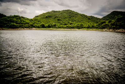 Scenic view of river against cloudy sky