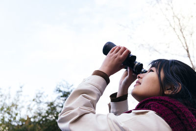 Young woman looking at sky through binoculars