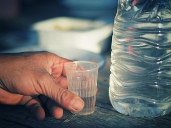 Cropped image of person holding glass jar on table