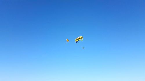 Low angle view of kite flying against clear blue sky