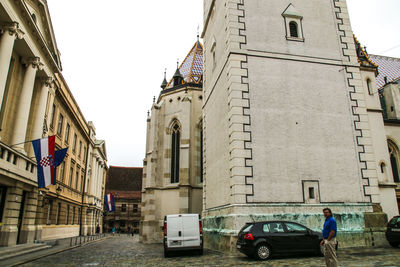 Cars on street amidst buildings in city against sky