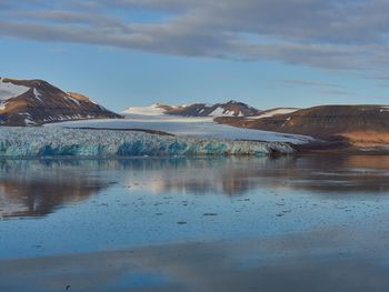 Scenic view of lake by snowcapped mountains against sky