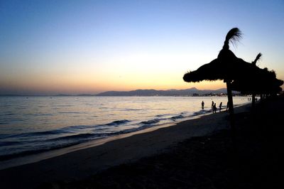 Silhouette woman on beach against clear sky during sunset