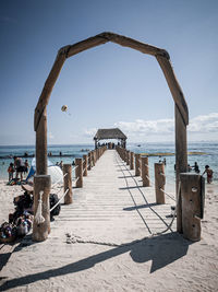 Wooden pier on beach against sky