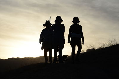 Silhouette of women walking on field