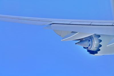 Low angle view of jet engine airplane flying against clear blue sky