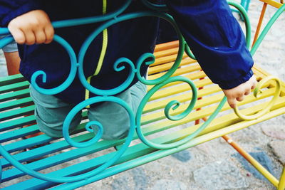 Midsection of child kneeling on bench at park