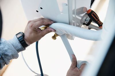 Man is installing wall compressor of air conditioner during hot season