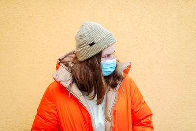 Portrait of young woman standing against wall during winter