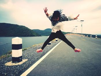 Full length of girl jumping against sky