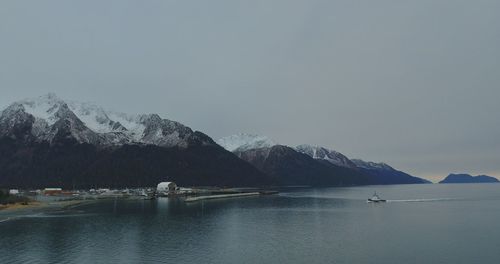 Scenic view of sea and snowcapped mountains against sky