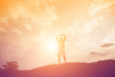 Silhouette woman standing on field against sky during sunset