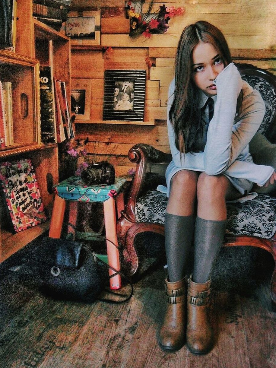 PORTRAIT OF BEAUTIFUL YOUNG WOMAN SITTING ON FLOOR IN SHELF