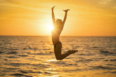Young woman jumping against sky during sunset
