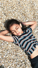 High angle view of girl sleeping on pebbles at beach