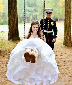 Portrait of beautiful bride swinging against navy officer