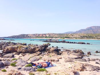 Boats in sea against clear blue sky