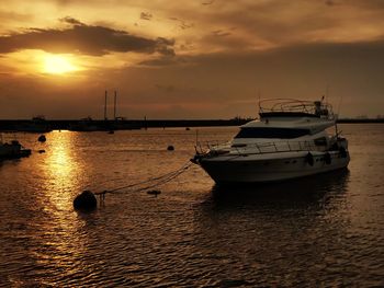 Sailboat moored on sea against sky during sunset