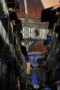 Illuminated lanterns hanging on street amidst buildings in city