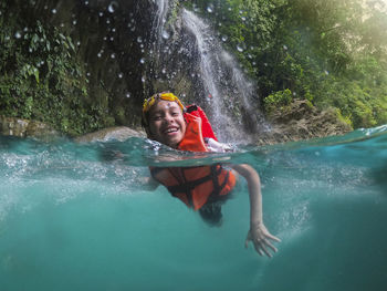 Boy swimming in crystal clear waters of the huasteca potosina. effect within the water and sky