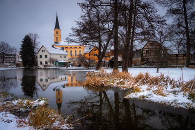 Canal amidst trees and buildings during winter