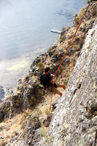 High angle view of man rock climbing against sea