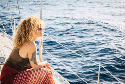 Young woman sitting on sailboat at sea shore