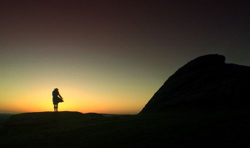 Silhouette of woman standing at sunset