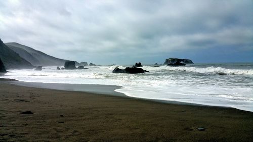 Scenic view of light on beach and the sea against cloudy blue sky