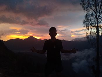 Silhouette man standing on mountain against sky during sunset