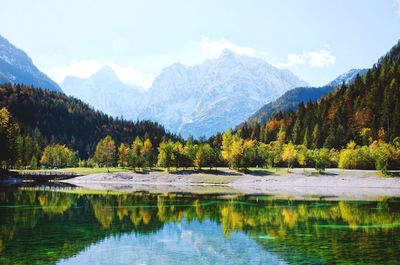 Scenic view of the snow-covered mountains and autumn forest, reflected in the green lake jasna.