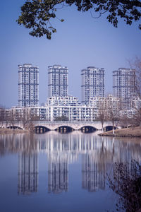 Reflection of buildings in lake against clear sky