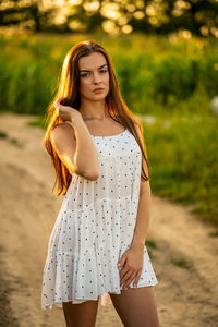 Young beautiful woman in white dress in corn field.