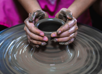 Midsection of woman making pottery in workshop