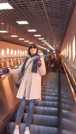Woman in warm clothing standing on escalator