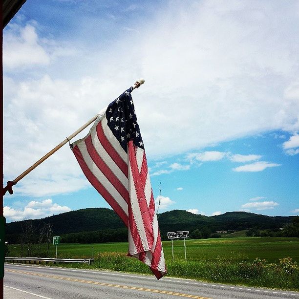 sky, grass, flag, cloud, cloud - sky, patriotism, tree, identity, field, american flag, national flag, red, day, blue, outdoors, landscape, cloudy, no people, nature, pole