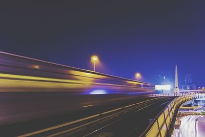 Light trails on railway tracks against clear sky at night