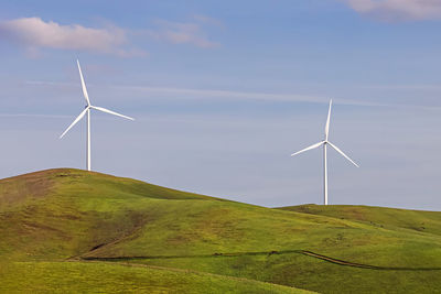 Windmills on field against sky