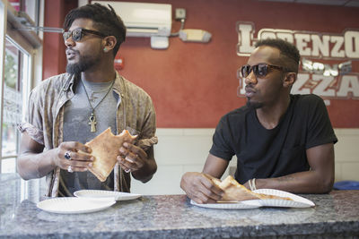 Two young men eating pizza in a restaurant.