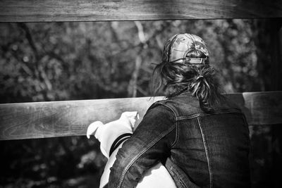 Rear view of woman with dog by fence