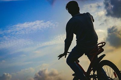 Low angle view of man riding bicycle against sky