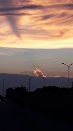 Silhouette street light against orange sky