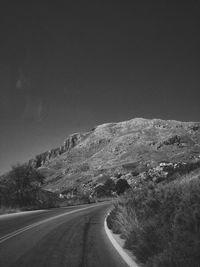 Highway by mountain against sky