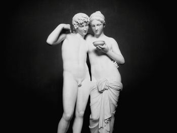 Young couple standing against black background