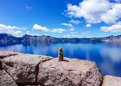 Rocks by lake against blue sky