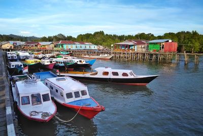 Boats moored at harbor against sky in city