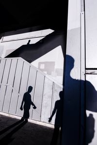 Silhouette man walking by building on sunny day