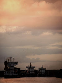 Commercial dock against cloudy sky during sunset