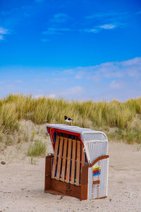 Hooded chairs on beach against blue sky